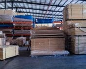Stacks of shrink-wrapped bamboo plywood sheets arranged on pallets in a bright warehouse environment supplied by HTR Bamboo.