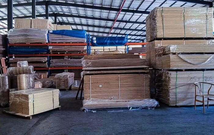 Stacks of shrink-wrapped bamboo plywood sheets arranged on pallets in a bright warehouse environment supplied by HTR Bamboo.